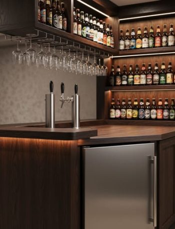 Finished basement home bar in a Kitchener house with a kegerator and taps, craft beer bottle display shelving, and organized glassware in warm lighting.